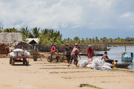 MADAGASCAR OCTOBER 18.2016 Malagasy peoples on Maroantsetra main street with firewood market and traditional huts. Wood is used for cooking on fire. Peoples everyday life in Madagascar. October 18. 2016, Madagascar, Toamasina Provinceのeditorial素材