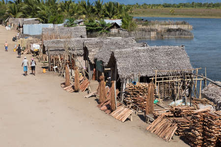 MADAGASCAR OCTOBER 18.2016 Malagasy peoples on Maroantsetra main street with firewood market and traditional huts. Wood is used for cooking on fire. Peoples everyday life in Madagascar. October 18. 2016, Madagascar, Toamasina Provinceのeditorial素材