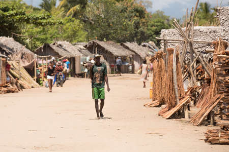 MADAGASCAR OCTOBER 18.2016 Malagasy peoples on Maroantsetra main street with firewood market and traditional huts. Wood is used for cooking on fire. Peoples everyday life in Madagascar. October 18. 2016, Madagascar, Toamasina Provinceのeditorial素材