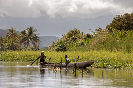 MADAGASCAR OCTOBER 19.2016 Malagasy countryside people from village transport freight by Traditional handmade dugout wooden boat. Everyday life on the river. Maroantsetra October 19. 2016, Madagascar.のeditorial素材