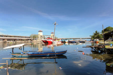 poor houses with sheet tin by the river with boats on the river,Kota Manado, North Sulawesi, Indonesiaの写真素材