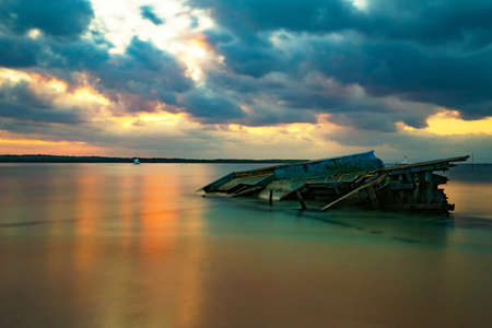 Idylic Bali sea, Nusa Penida Island, Toyaeh, Indonesia stranded boat silhouette at evening with dramatic skyの写真素材