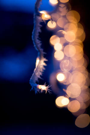 white christmas lights on roof against dark background with icing and hoarfrost	and bokehの写真素材
