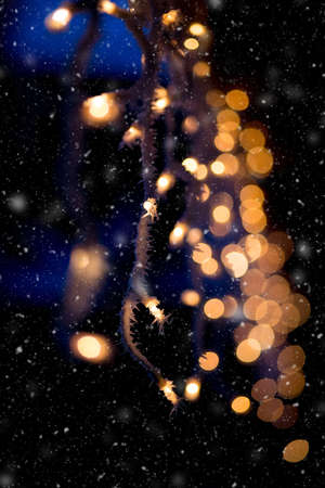 white christmas lights on roof against dark background with icing and hoarfrost	and snowfallの写真素材