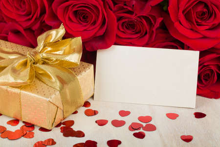 Valentine gift with bouquet of fresh red roses and small red hearts. Love concept.の写真素材