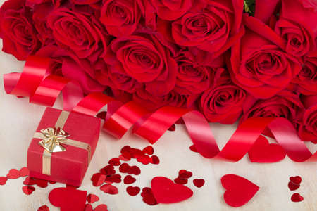 Valentine gift with bouquet of fresh red roses and small red hearts. Love concept.の写真素材