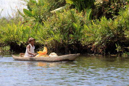 MADAGASCAR OCTOBER 19.2016 Malagasy countryside people from village transport freight by Traditional handmade dugout wooden boat. Everyday life on the river. Maroantsetra October 19. 2016, Madagascar.のeditorial素材
