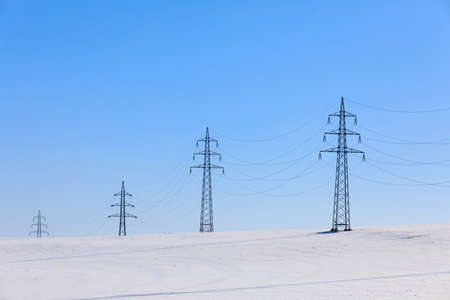 high voltage power lines in winter landscape against a blue skyの写真素材