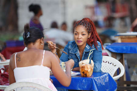 TOAMASINA, MADAGASCAR - OCTOBER 17, 2016: Street life in  Madagascar second largest city Toamasina. Beautifull girls dinner at a street stall in Toamasina, Madagascar October 17. 2016のeditorial素材