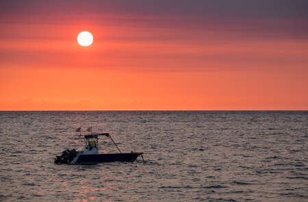 Sunset over Madagascar Nosy be beach with boat silhouette. Africa vacation travel concept.