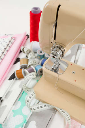 detail of Sewing machine, cotton cotton fabric and tailor measurement tape with spools of thread...