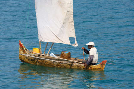 NOSY BE ,MADAGASCAR - NOVEMBER 3.2016 Malagasy man on sea in traditional handmade dugout wooden sailing boat. Everyday life on Nosy be island. Nosy be, Madagascar, November 3. 2016のeditorial素材