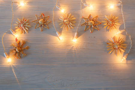 white christmas lights as retro vintage wooden background with straw decoration and snow effectの写真素材