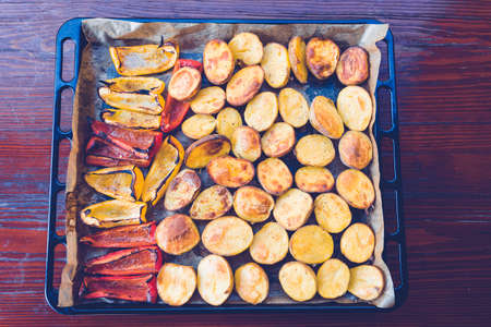 Delicious baked potato and pepper with plate on wooden desk. Traditional garnish or side dish for beef steak. Country-style roasted potatoesの写真素材