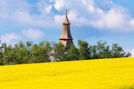 Beautiful spring rural agriculture landscape with small church, rape field and blue skyの写真素材