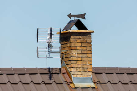 chimney from bricks in the house and TV antennaの写真素材