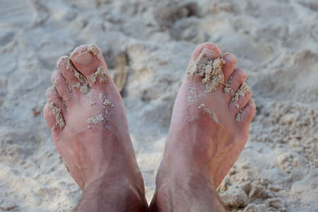 mans feet on sand beach, summer vacation concept