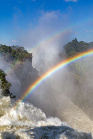Rainbow on Victoria falls after rain season in May, waterfall is full of water, everywhere is mist, Zambia Zimbabwe border, Africa wilderness landscape. Wonder of the Worldの写真素材