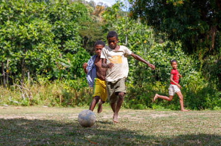 Maroantsetra, Madagascar - November 23 2016: Happy Malagasy children, boys and girls with bare feet play soccer behind his village, near Masoala rainforest in Madagascar.のeditorial素材