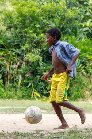 Maroantsetra, Madagascar - November 23 2016: Happy Malagasy children, boys and girls with bare feet play soccer behind his village, near Masoala rainforest in Madagascar.のeditorial素材