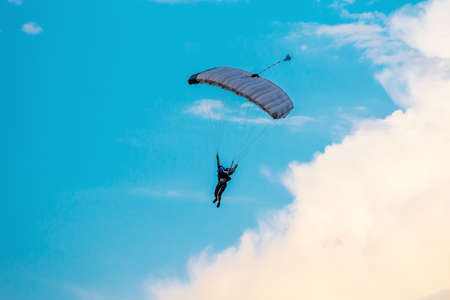 Parachutist falling from the sky in evening sunset dramatic sky. Recreational sport, Paratrooper silhouette on colored sky.の写真素材
