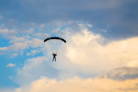Parachutist falling from the sky in evening sunset dramatic sky. Recreational sport, Paratrooper silhouette on colored sky.の写真素材