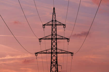 sunset with electricity tower in countryside. Summer scene. Dusk sky with sun. Spring sunset