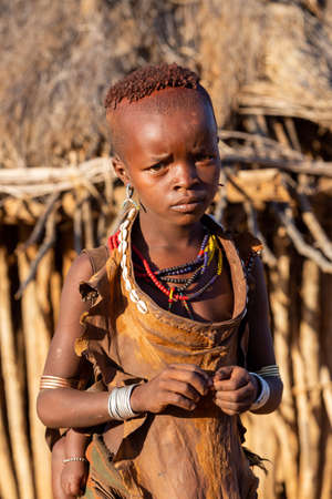 Turmi, Omo River Valley, Ethiopia - May 10, 2019: Portrait of a Hamar children with with baby on...