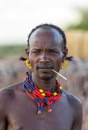 Turmi, Omo River Valley, Ethiopia - May 10, 2019: Portrait of a Hamar man in village. The Hamer are a primitive tribe and the women have many decorations. South Ethiopia Africaのeditorial素材
