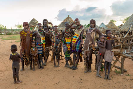 Turmi, Omo River Valley, Ethiopia - May 10, 2019: Portrait of a Hamar woman and children in village. The Hamer are a primitive tribe and the women have many decorations. South Ethiopia Africaのeditorial素材