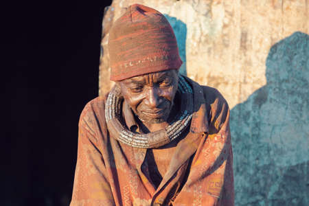 NAMIBIA, OMUSATI REGION, MAY 6: Wrinkled Himba old man, village chief with thoughtful look front of...
