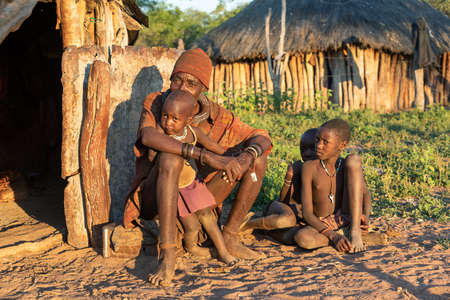 NAMIBIA, OMUSATI REGION, MAY 6: Wrinkled Himba old man with children in front of the hut. The Himba...