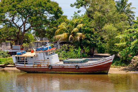 old rusted abandoned boat moored in a lagoon on a river in Maroantsetra, Madagascar. Rural...
