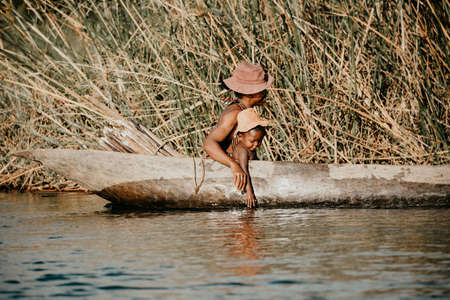 MADAGASCAR OCTOBER 18.2016 Malagasy woman with children from village transport freight by Traditional handmade dugout wooden boat. Daily life on the river. Maroantsetra October 18. 2016, Madagascar.のeditorial素材