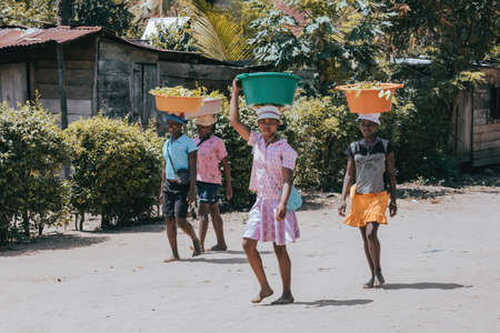MAROANTSETRA, MADAGASCAR OCTOBER 20.2016: Malagasy woman carry heavy loads on head. The traditional method of transport of goods in Africa. October 20. 2016, Madagascarのeditorial素材