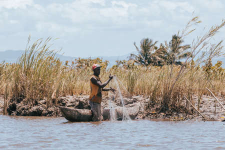 MAROANTSETRA, MADAGASCAR OCTOBER: 19.2016: Native malagasy man fishing on river, using technique pulling net from boat. Daily life of peoples in Madagascar countryside. October 19. 2016, Madagascarのeditorial素材