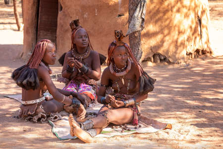 NAMIBIA, KAMANJAB, MAY 6: Bored Himba women in village posing to tourists near Kamanjab in northern Namibia, May 6, 2018, Namibiaのeditorial素材