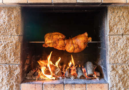 chicken roasting on a spit in garden grill with open fireの写真素材