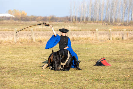 HORTOBAGY, HUNGARY, NOVEMBER, 04. 2018: Hungarian csikos in traditional folk costume showing off his trained horse. Traditional Horse-herdsman of Hungary. November 04. 2018, Hortobagy, Hungaryのeditorial素材