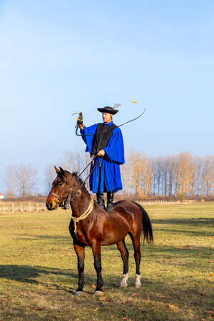 HORTOBAGY, HUNGARY, NOVEMBER, 04. 2018: Hungarian csikos in traditional folk costume showing off his trained horse. Traditional Horse-herdsman of Hungary. November 04. 2018, Hortobagy, Hungaryのeditorial素材