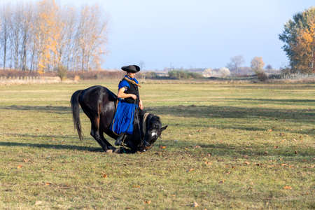 HORTOBAGY, HUNGARY, NOVEMBER, 04. 2018: Hungarian csikos in traditional folk costume showing off his trained horse. Traditional Horse-herdsman of Hungary. November 04. 2018, Hortobagy, Hungaryのeditorial素材