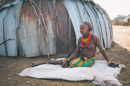 Omorate, Omo Valley, Ethiopia - May 11, 2019: Woman from the African tribe Dasanesh resting in...