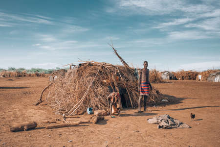 Omorate, Omo Valley, Ethiopia - May 11, 2019: Man from the African tribe Dasanesh in front of his hut. Daasanach are Cushitic ethnic group inhabiting in Ethiopia, Kenya, and South Sudanのeditorial素材