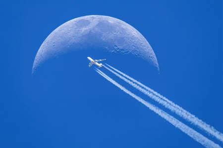 Passenger plane - airliner passes near the moon. Explore new frontier. Space traveler conceptの写真素材