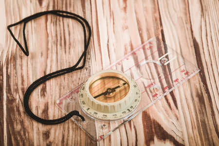 old transparent plastic sport compass with azimuth measurement on wooden backgroundの写真素材