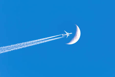 Passenger plane - airliner passes near the moon. Explore new frontier. Space traveler conceptの写真素材