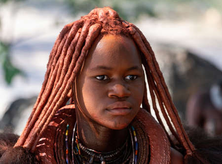 NAMIBIA, OMUSATI REGION, MAY 7: Portrait of Himba woman with traditional hairstyle and red clay...
