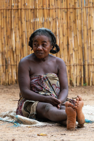 Bekopaka, Madagascar - November 5, 2022: Elder Malagasy woman relaxing in front of hut, there is no job opportunity here. Everyday life on the Madagascar countryside.のeditorial素材