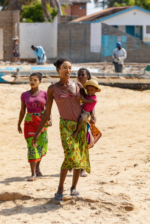 Morondava, Madagascar - November 3, 2022: Malagasy woman with her face painted against the sun and a child in her arms walks along the beach in Morondava.のeditorial素材