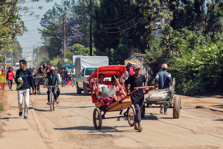 Antsirabe, Madagascar - November 10, 2022: Traditional rickshaw bicycle with Malagasy people on the street of Antsirabe, one of the ways to earn money. Everyday life on the streets of Madagascar.のeditorial素材